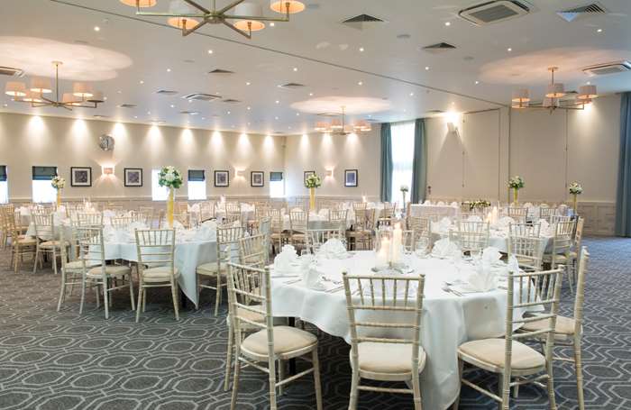 Brightly lit wedding reception venue at Staverton Park Hotel, with round tables set up with white tablecloths